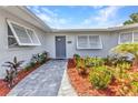 Inviting front entrance with a gray brick walkway leading to the front door with colorful plants at 4244 Harbor Blvd, Port Charlotte, FL 33952