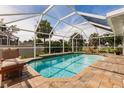 Inviting screened-in pool area with a waterfall feature, brick pavers, and comfortable lounge seating at 437 South Dr, Punta Gorda, FL 33950