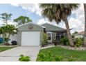 Charming home featuring a light green exterior, a one-car garage, and a cozy front porch at 477 Ricold Ter, Port Charlotte, FL 33954