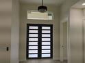 Home interior highlighting the modern front door and elegant overhead lighting fixture at 136 Sequoyah Dr, Port Charlotte, FL 33954