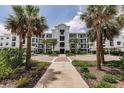 Stunning exterior of a light blue mid-rise condo complex with lush landscaping and palm trees at 14141 Heritage Landing Blvd # 921, Punta Gorda, FL 33955