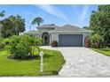 Charming single-story home with a brick driveway and lush landscaping at 149 Crevalle Rd, Rotonda West, FL 33947
