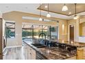 Gourmet kitchen boasts granite countertops, stainless steel appliances, and panoramic views of the serene lake at 170 Antilla Dr, Rotonda West, FL 33947