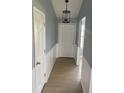 Hallway with modern chandelier, wainscoting, neutral paint and flooring leading to the front door at 1708 Blue Lake Cir, Punta Gorda, FL 33983