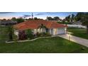 Charming home featuring lush landscaping, a vibrant tile roof, and a well-manicured lawn at 23141 Corvin Ave, Port Charlotte, FL 33954
