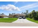 Inviting single-story home featuring a long driveway, manicured lawn, mature trees, and an attached garage at 2329 Como St, Port Charlotte, FL 33948