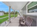 Covered porch with white railing, gray metal siding, and views of the lawn and small garden at 369 Hyacinth St, Port Charlotte, FL 33954