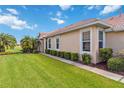 Well-manicured lawn and landscaped bushes line the sidewalk of this home with white trim at 4567 Whispering Oaks Dr, North Port, FL 34287