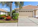 A well-maintained two-car garage with a tile roof sits next to a palm tree in the front yard at 4567 Whispering Oaks Dr, North Port, FL 34287