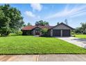 Charming single-story home with a lush green lawn, mature trees, and a two-car garage at 5052 Kingsley Rd, North Port, FL 34287
