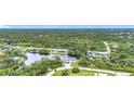 An aerial view of the white house with a paver driveway, two car garage, and luscious green trees at 576 Mcdill Dr, Port Charlotte, FL 33953