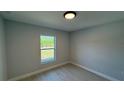 Neutral-toned bedroom with wood-look flooring, a window with a backyard view, and ample natural light at 7052 Legion St, Port Charlotte, FL 33981