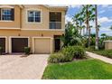 Townhome with a multi-car garage, second-floor balcony, and professionally maintained lush tropical landscaping at 8098 Moonstone Dr # 17-203, Sarasota, FL 34233