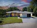 Single-story home with a two-car garage, well-lit entry, and manicured lawn at 875 Bayshore Dr, Englewood, FL 34223
