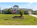 Quaint home featuring a well-kept lawn, mature landscaping, and an American flag at 11068 Jacqueline Ave, Englewood, FL 34224