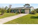 Charming single-story home with green exterior, manicured lawn, and attached garage at 11068 Jacqueline Ave, Englewood, FL 34224