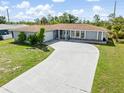 Inviting single-story home with long driveway, lush lawn, and welcoming entrance in a serene setting at 123 Annapolis Ln, Rotonda West, FL 33947