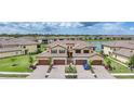 An exterior view showcases tan-colored homes with red-tiled roofs, landscaped grounds, and a serene pond in the background at 12425 Ghiberti Cir # 101, Venice, FL 34293