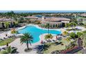 An aerial view highlights a large community pool surrounded by palm trees, lounge chairs, and well-maintained landscaping at 12425 Ghiberti Cir # 101, Venice, FL 34293