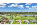 Aerial view of a home on a golf course with a lake in the background and lush greenery at 1915 Pebble Beach Ct, Venice, FL 34293