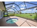 Enclosed patio with in-ground jacuzzi tub and scenic view of golf course in background at 1915 Pebble Beach Ct, Venice, FL 34293