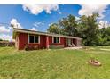 View of house featuring a vibrant red exterior, blue garage door, and well-maintained lawn at 20409 Emerald Ave, Port Charlotte, FL 33952