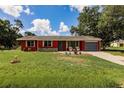 Charming single-story home features a vibrant red exterior, blue garage door, and well-maintained lawn at 20409 Emerald Ave, Port Charlotte, FL 33952