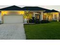 Charming home with a two-car garage, palm trees, manicured landscaping, and a patterned concrete driveway at 260 Rotonda E Blvd, Rotonda West, FL 33947