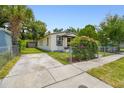 Side yard exterior with a chain-link fence, lovely flowers, and off-street parking at 2626 E 38Th Ave, Tampa, FL 33610