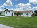 Well-maintained single-story home with a green lawn, palm trees, and tidy landscaping at 724 Hartford Nw Dr, Port Charlotte, FL 33952