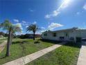 Single-story home with a well-maintained lawn and a variety of beautiful palm trees at 2336 Picnic St, Port Charlotte, FL 33952