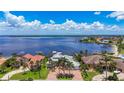 An aerial view of a stunning waterfront home with palm trees and a brick driveway at 119 Creek Se Dr, Port Charlotte, FL 33952