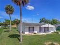 Inviting single-story home with purple shutters, well-manicured lawn, and mature palm trees at 1389 Hinton St, Port Charlotte, FL 33952