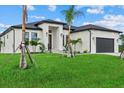 A modern home featuring a well-kept lawn, enhanced by striking palm trees and an attached two-car garage at 14166 Fort Worth Cir, Port Charlotte, FL 33981
