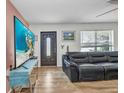 Comfortable living room featuring a plush leather sofa, a modern ceiling fan and a large window at 1478 Harmony Dr, Port Charlotte, FL 33952