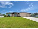 Inviting single-Gathering home with a large three-car garage, stone details, and lush green lawn at 15741 Autry Cir, Port Charlotte, FL 33981