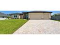 Well-maintained home featuring a spacious three-car garage and a patterned brick driveway leading up to the entrance at 15741 Autry Cir, Port Charlotte, FL 33981