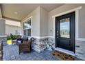 Inviting covered front porch featuring stone accents, comfortable seating, and stylish decor at 16833 Terrapin Key Dr, Port Charlotte, FL 33953