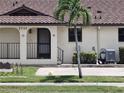 Up close exterior view of condo building with tan stucco, dark trim, tile roof and lush green landscaping at 2732 Magdalina Dr # C, Punta Gorda, FL 33950