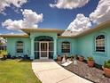 Inviting turquoise home exterior featuring a screened entry, well-manicured lawn and landscaping with potted plants at 2969 Wells Ave, North Port, FL 34286