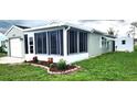 The back of this home has a large screened-in lanai, surrounded by grass, and is well maintained at 426 Ricold Ter, Port Charlotte, FL 33954