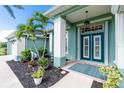 Inviting front entrance with a blue-green door, white columns, and manicured landscaping at 9954 Audrey St, Port Charlotte, FL 33981