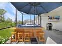 Relaxing backyard with a hot tub, outdoor kitchen, tv and seating under the shade of an umbrella at 11383 Burgundy Dr, Venice, FL 34293