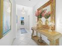 Bright hallway featuring a decorative table with mirror and chandelier, and tiled floors at 11383 Burgundy Dr, Venice, FL 34293