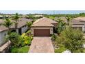 Well-maintained single Gathering home with tile roof and brick driveway surrounded by palm trees at 13935 Campoleone St, Venice, FL 34293