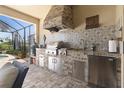 Outdoor kitchen featuring stainless steel appliances, a built-in grill, and tile backsplash at 13935 Campoleone St, Venice, FL 34293