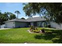 Charming single-story home featuring a well-manicured lawn, a two car garage, and fountain at 15037 Mcgraw Ave, Port Charlotte, FL 33953