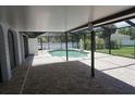 A screened in pool deck shows a well designed brick patio and lovely pool view at 15037 Mcgraw Ave, Port Charlotte, FL 33953