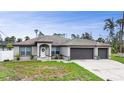 Inviting one-story home showcasing a well-maintained lawn, manicured shrubs, and three-car garage at 1546 Gourmet Rd, North Port, FL 34288