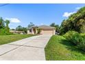 Well-kept home with a long driveway leading to an attached two-car garage and lush green lawn at 1693 Jagust Rd, North Port, FL 34288
